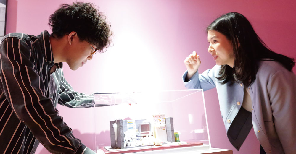 「Mozuミニチュア展 ようこそ、ちいさな世界へ。」の内覧会にて。アーティストのMozuさんと作品のチェックを行う佐藤さん。