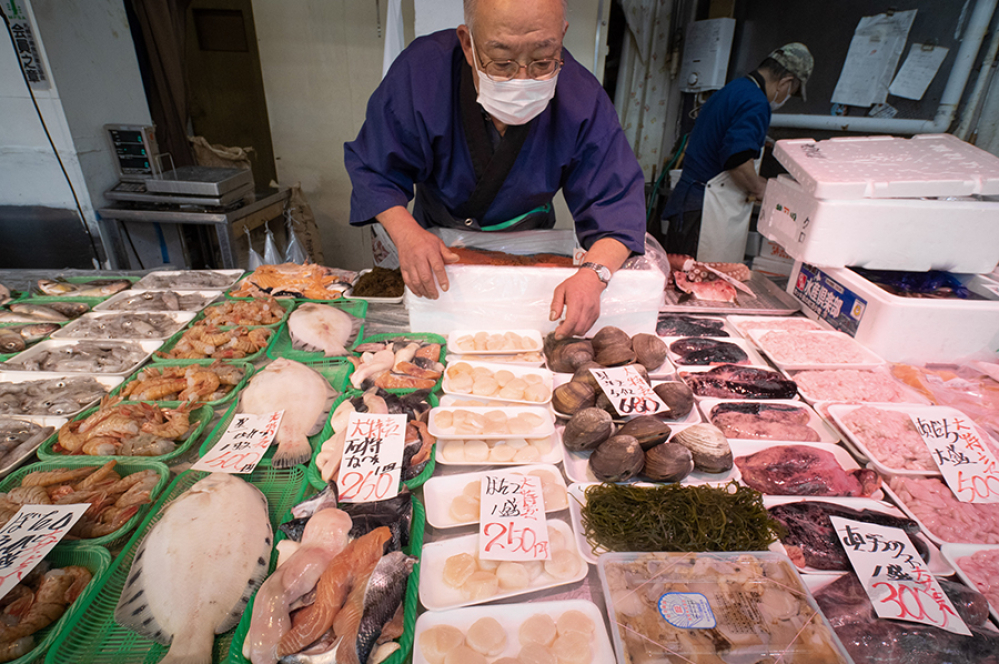朝、市場で仕入れた魚を並べる新八田中商事の竹田雅彦さん。魚のことなら何でも相談に乗る。