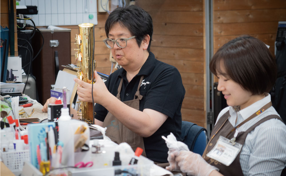 三響楽器のリペアマン、小梁川匠さん（左）はこの道35年のベテラン。 隣の種市泉水さんはリペアの仕事をして４年目。どちらも元吹奏楽部員。