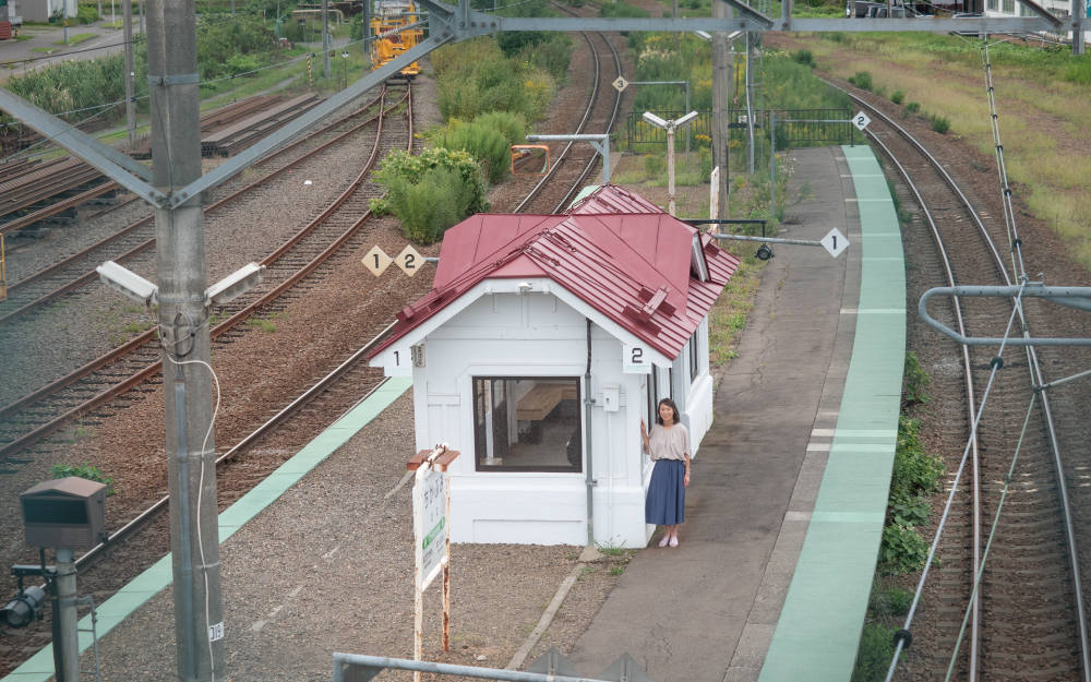 「羊と鋼の森」のロケ地、旭川・近文駅に佇む旭川地域フィルムコミッションの森崎真美恵さん。撮影時は築90年以上の木造待合所だったが、その後リニューアルされた
